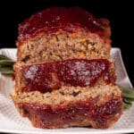 Venison meatloaf with carrots, mushrooms, celery bits, and herbs visible, topped with cranberry glaze.