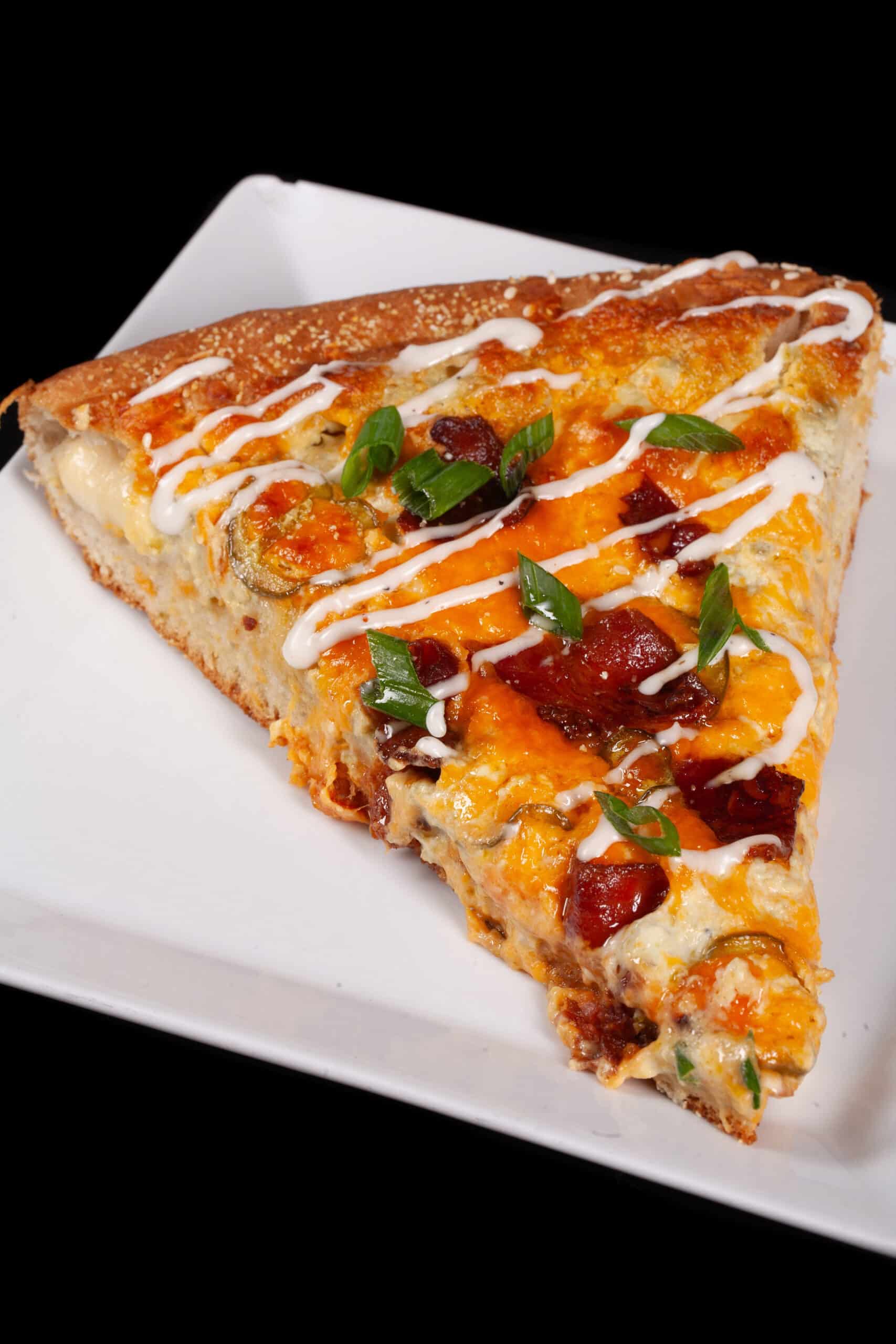 A stuffed crust bacon jalapeno popper pizza drizzled with ranch dressing and topped with sliced green onions.