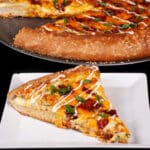 A stuffed crust bacon jalapeno popper pizza drizzled with ranch dressing and topped with sliced green onions.