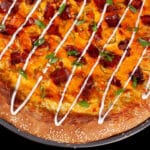 A bacon jalapeno popper stuffed crust pizza drizzled with ranch dressing and topped with sliced green onions.