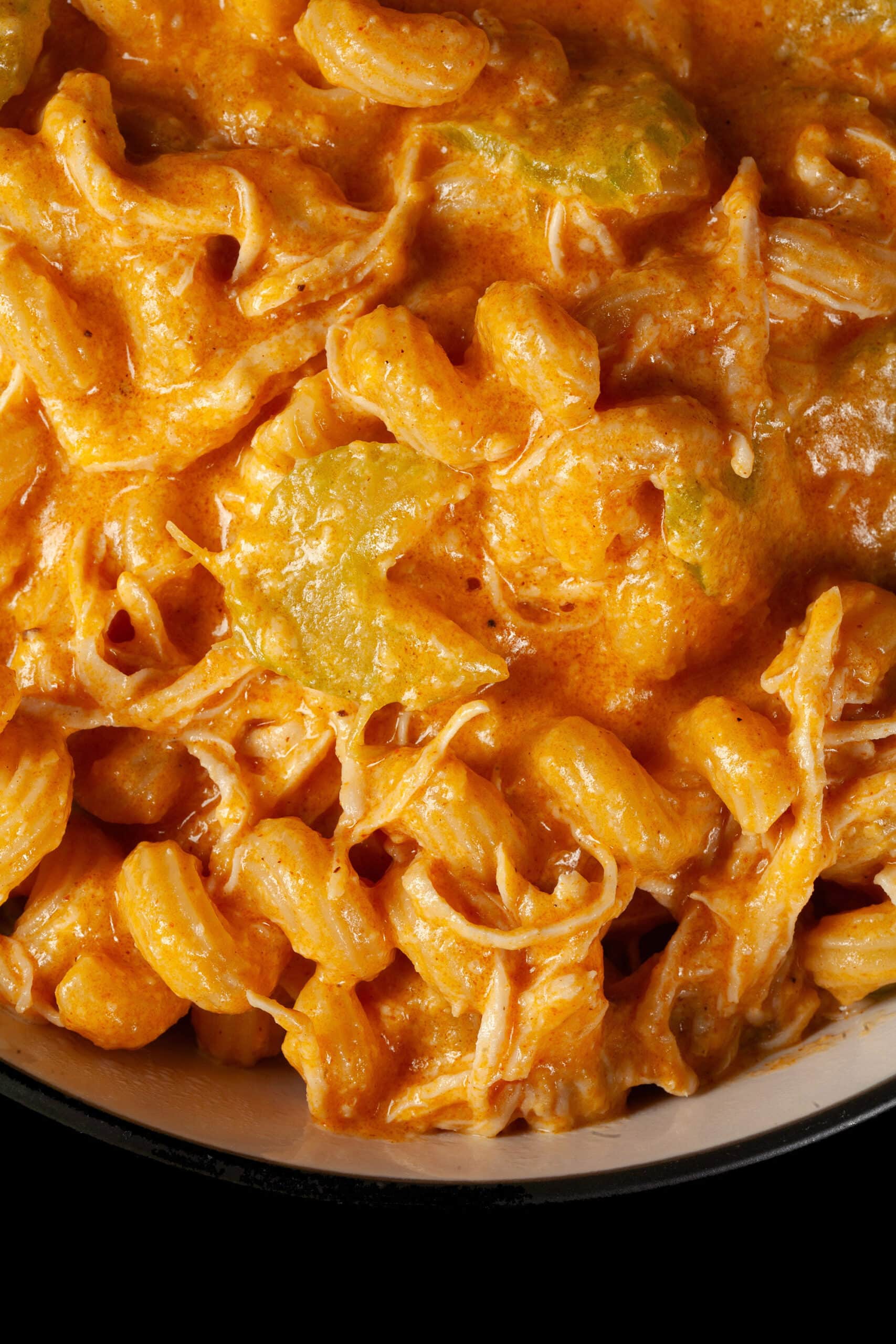 A bowl of Buffalo Chicken Macaroni and Cheese, with shredded chicken and celery visible in the cream sauce, and spiral pasta.
