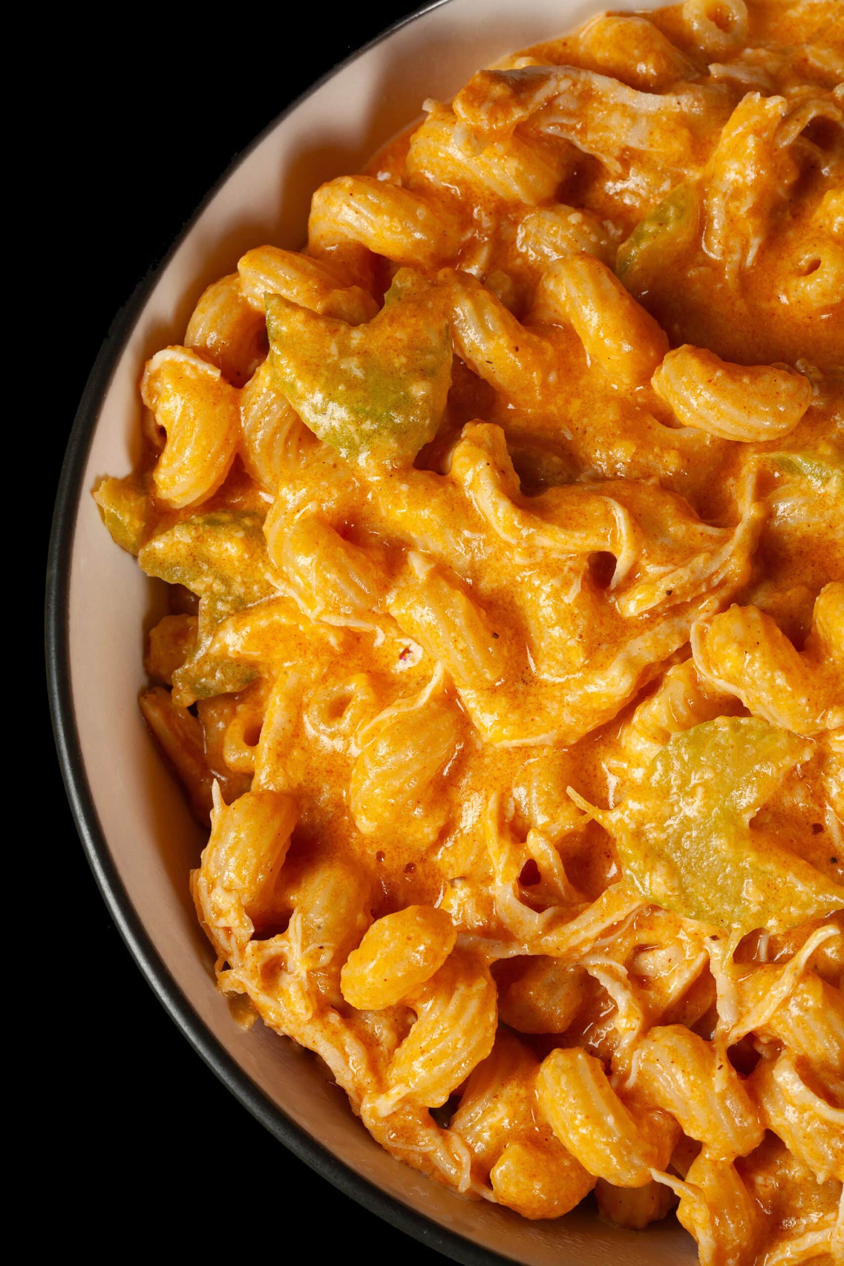 A bowl of Buffalo Chicken Macaroni and Cheese, with shredded chicken and celery visible in the cream sauce, and spiral pasta.