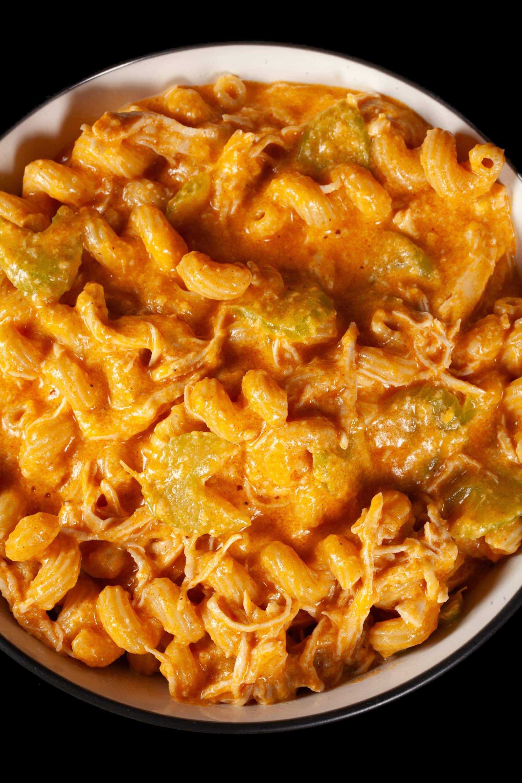 A bowl of Buffalo Chicken Macaroni and Cheese, with shredded chicken and celery visible in the cream sauce, and spiral pasta.