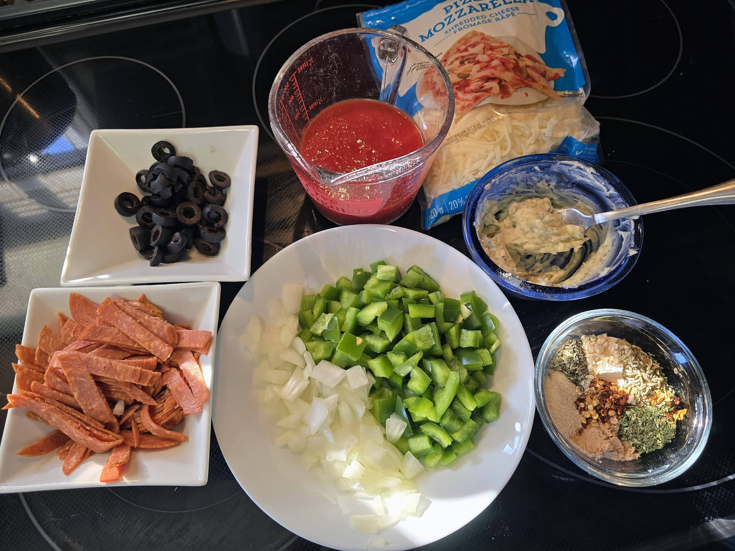 All of the ingredients for a batch of pizza sloppy joes, laid out on a stove top.