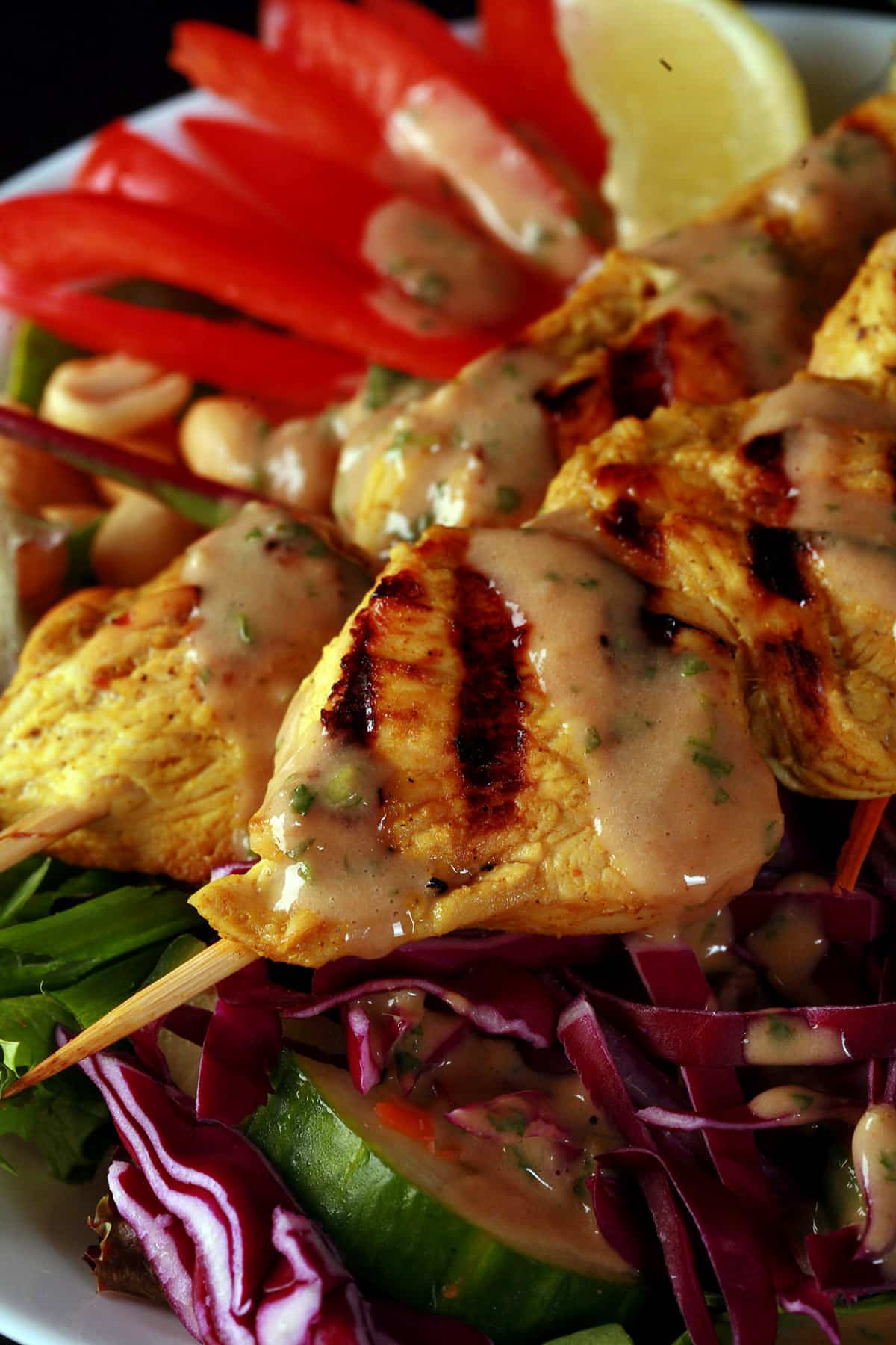 A grilled chicken satay salad drizzled with peanut dressing.