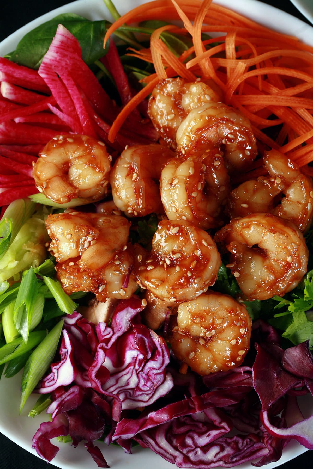 A colourful salad topped with honey ginger shrimp.