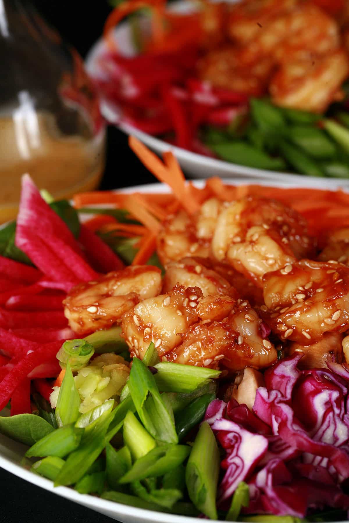A colourful salad topped with honey ginger shrimp.