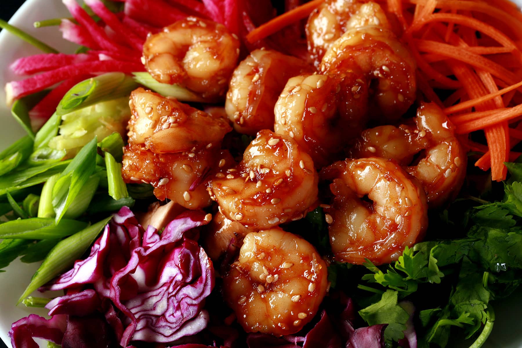 A colourful salad topped with honey ginger shrimp.