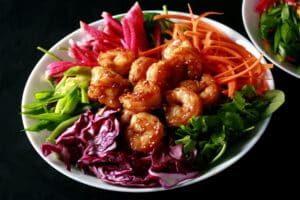A colourful salad topped with honey ginger shrimp.