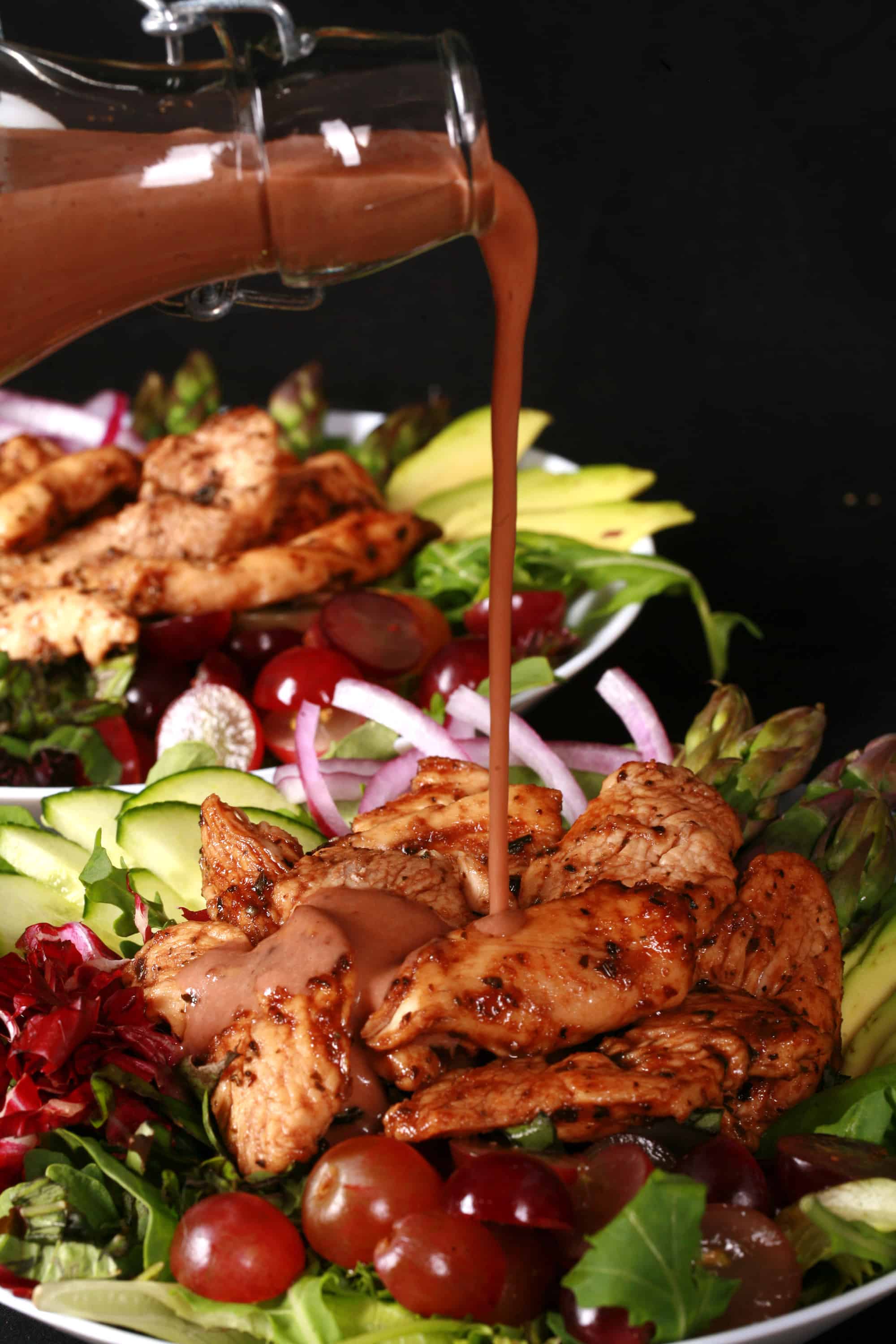 A balsamic chicken salad with red grapes and a bottle of homemade grape balsamic vinaigrette.