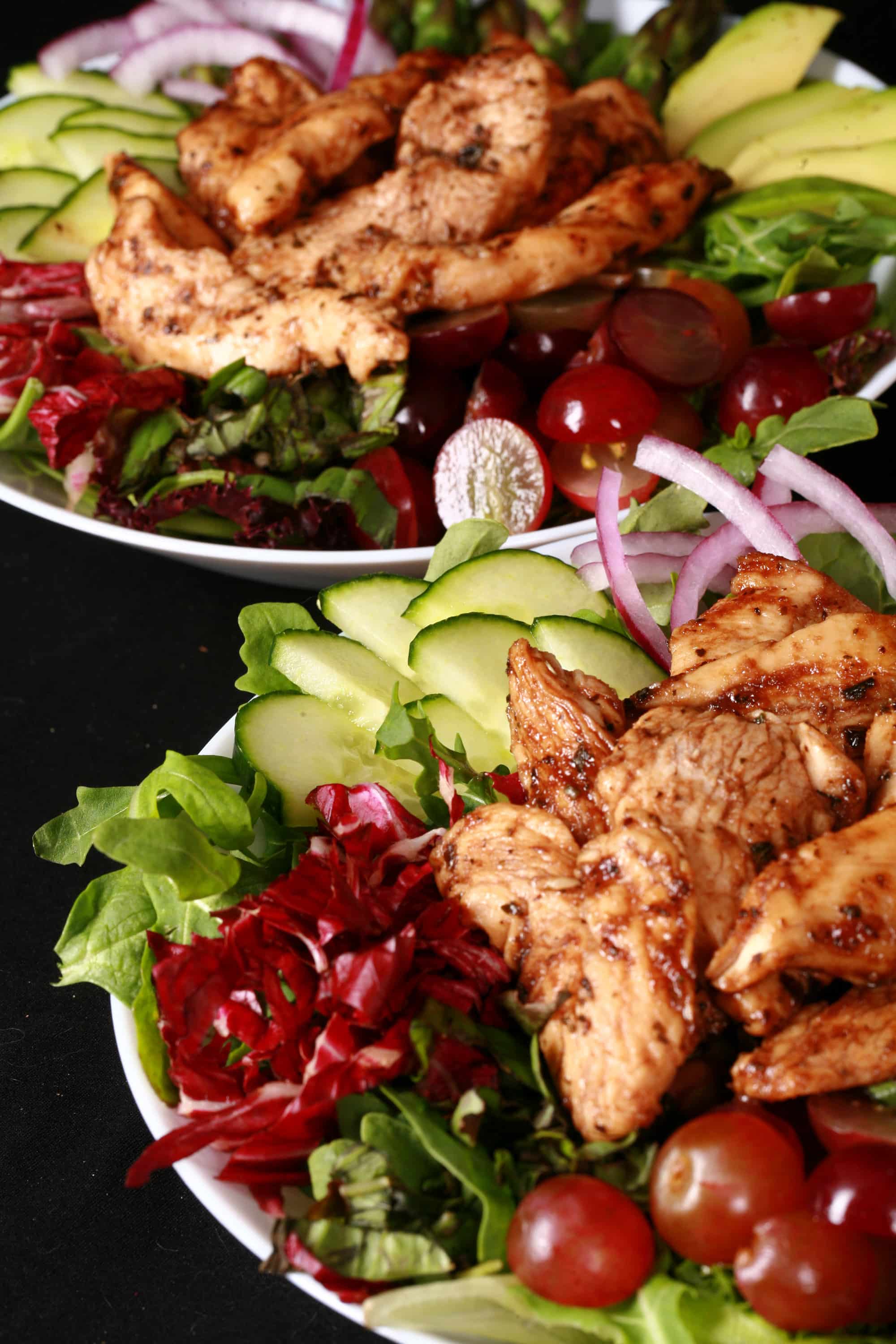 A balsamic chicken salad with red grapes and a bottle of homemade grape balsamic vinaigrette.