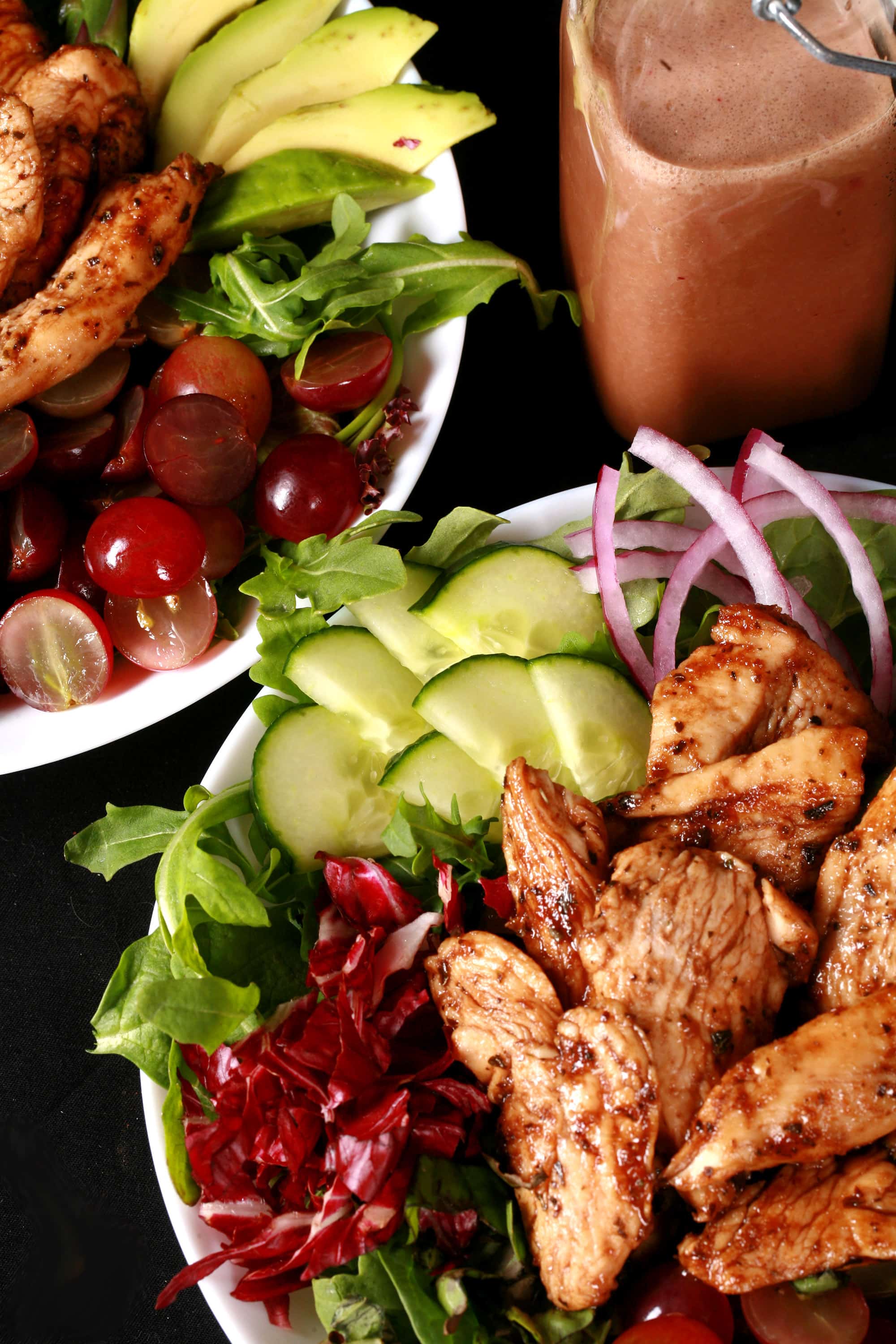 A balsamic chicken salad with red grapes and a bottle of homemade grape balsamic vinaigrette.