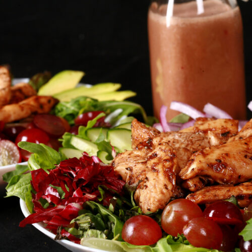 A balsamic chicken salad with red grapes and a bottle of homemade grape balsamic vinaigrette.