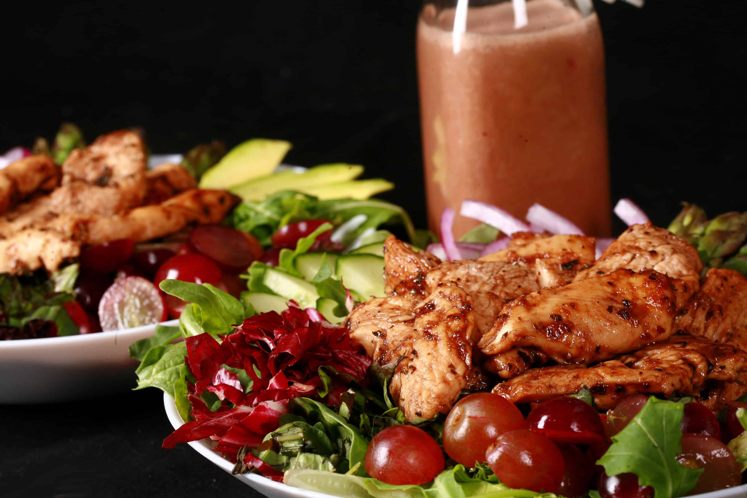 A balsamic chicken salad with red grapes and a bottle of homemade grape balsamic vinaigrette.