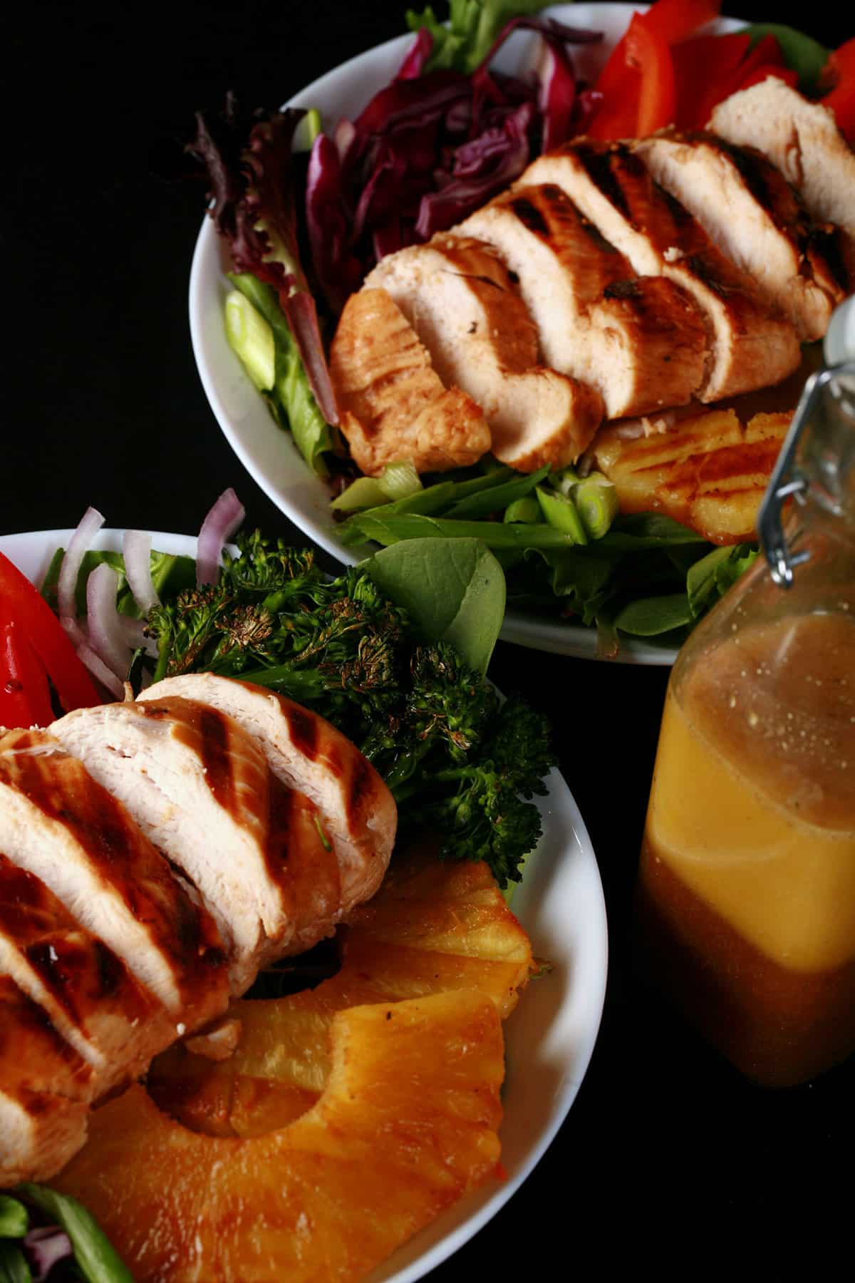 Two grilled chicken teriyaki salads with fresh pineapple.