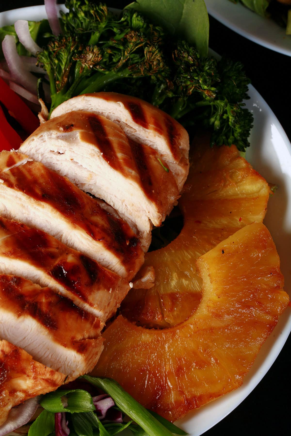A grilled teriyaki chicken salad with fresh pineapple slices.