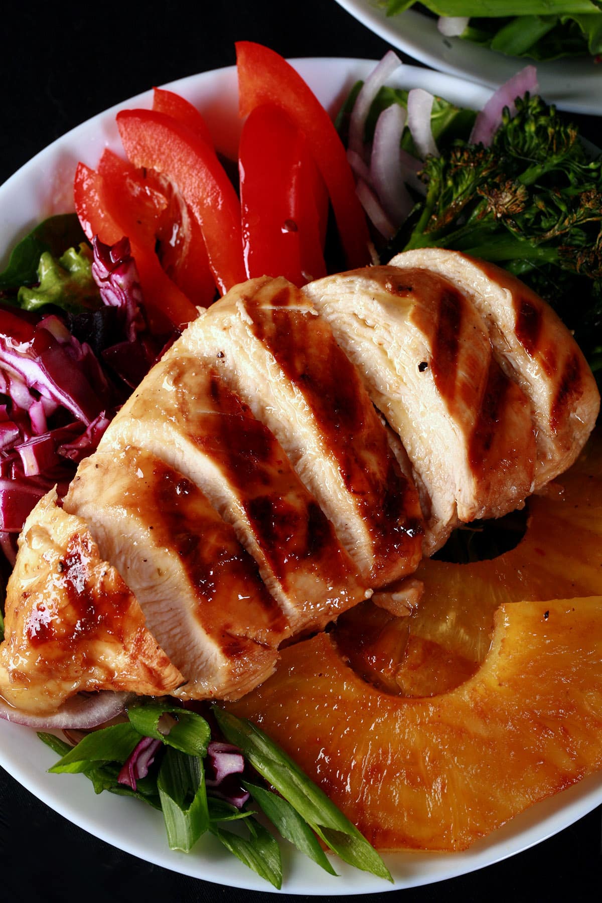 A grilled teriyaki chicken salad with fresh pineapple slices.