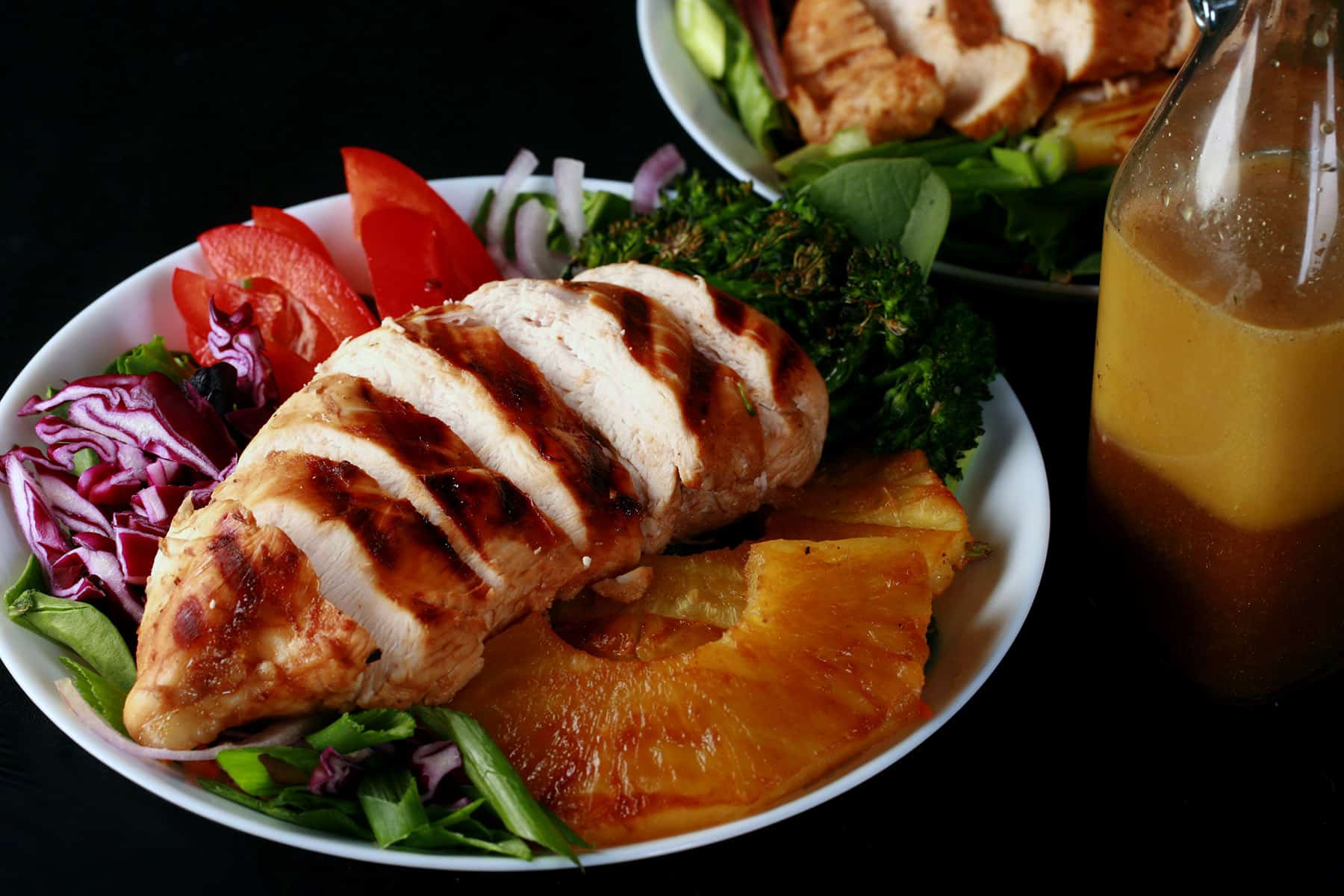 Two grilled chicken teriyaki salads with fresh pineapple.